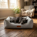 Gray plush square dog bed with dark cushion and brown logo patch