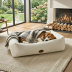 Cream bouclé pet nest bed with dog resting and plaid throw blanket