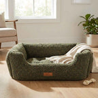 Orthopaedic dog bed in dark green textured fabric with raised bolsters and tan logo patch, empty